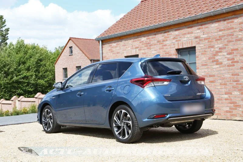Toyota Auris bleue (phase 2) garée devant une maison en briques